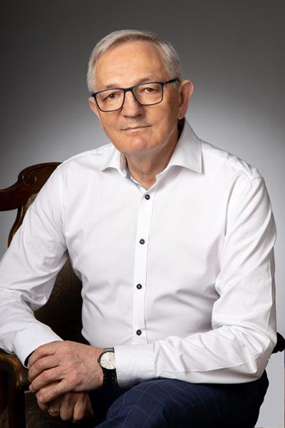 Fotografia przedstawia burmistrza Stefana Dziamarę. Mężczyzna o krótkich, siwych włosach, w okularach i białej koszuli, siedzi na stylowym krześle. Zdjęcie pochodzi z archiwum prywatnego.